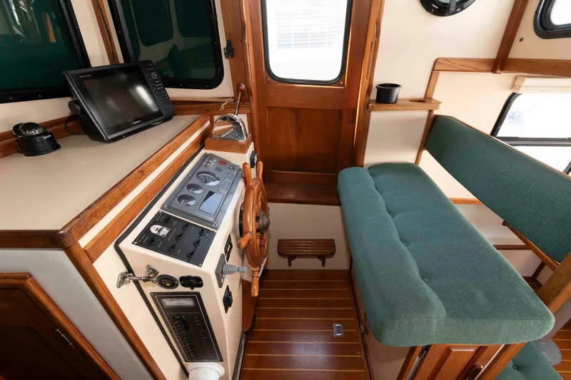Slide: The Image of Interior of a 1996 Nordic Tug 26, featuring helm, controls, and green cushioned seating. - 15