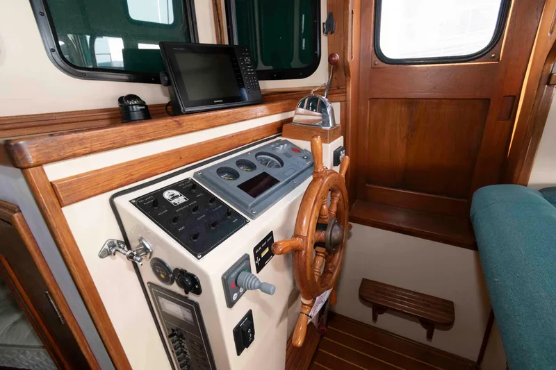 Slide: The Image of Interior helm of a 1996 Nordic Tug 26 with wooden steering wheel and navigation equipment. - 16