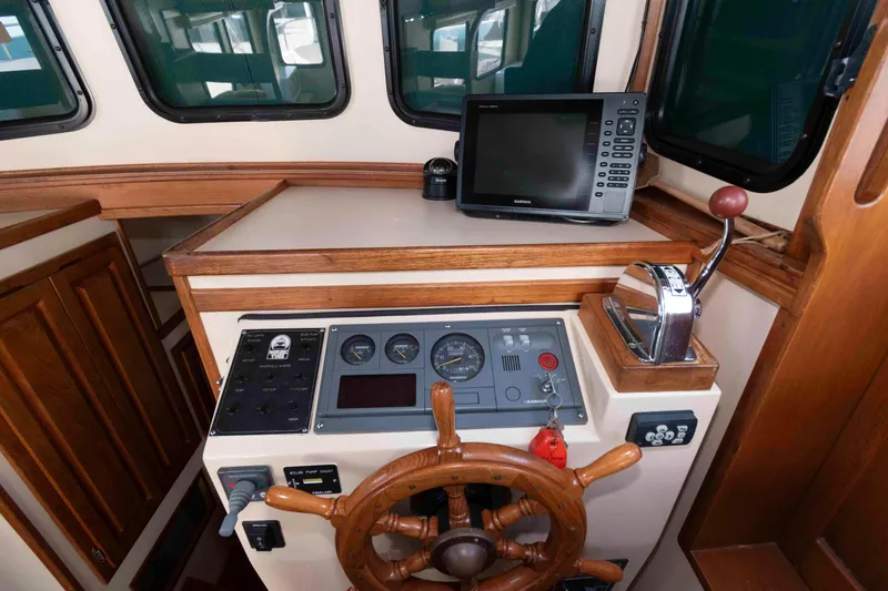 Slide: The Image of 1996 Nordic Tug 26 helm with wooden wheel, control panel, and navigation equipment. - 17