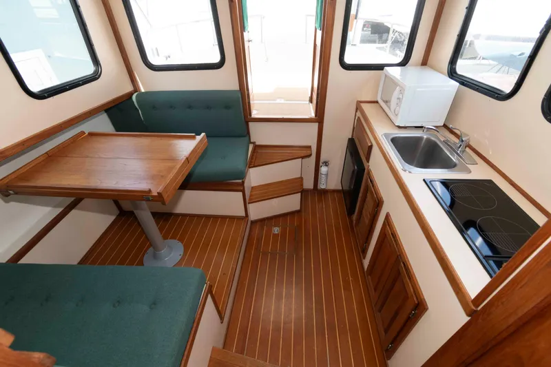 Slide: The Image of Interior of a 1996 Nordic Tug 26 featuring a compact kitchen and dining area. - 18