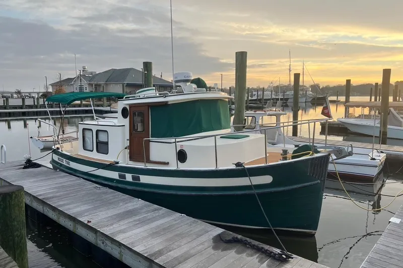 Slide: The Image of 1996 Nordic Tug 26 docked at marina during sunset, showcasing classic design and green accents. - 2