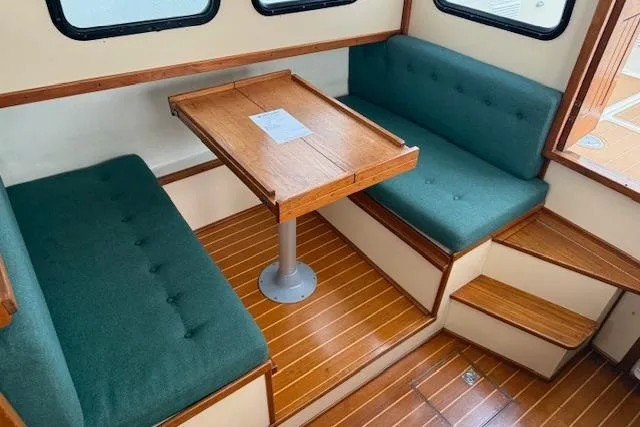 Slide: The Image of 1996 Nordic Tug 26 interior with green seating, wooden table, and steps. - 6