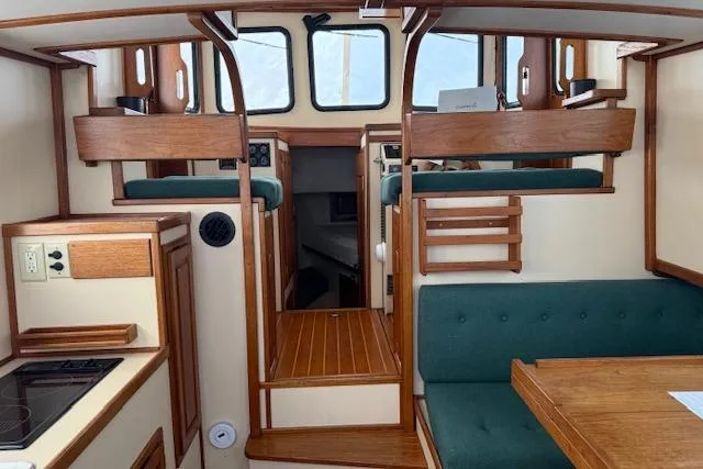 Slide: The Image of Interior of a 1996 Nordic Tug 26, featuring wood accents and green seating. - 8