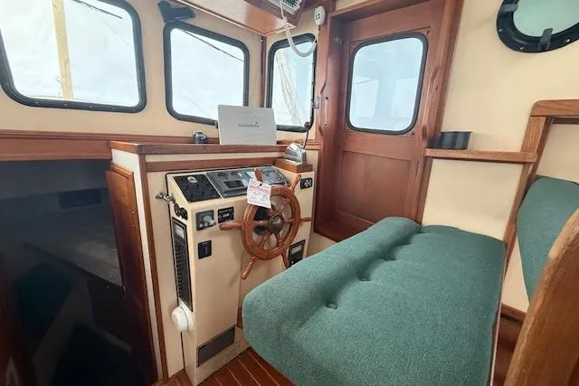 Slide: The Image of Interior of a 1996 Nordic Tug 26, featuring helm, wooden accents, and green seating. - 9