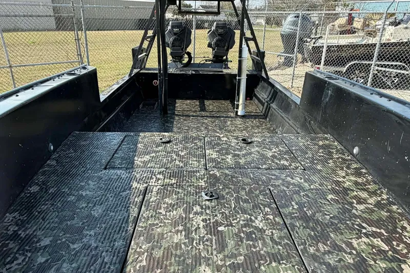 Slide: The Image of 2015 Custom 2175 Bowfishing boat with camo deck, dual seats, and fenced yard background. - 2