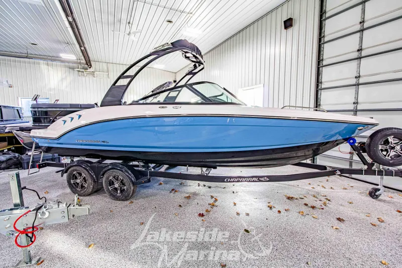 The Image of 2026 Chaparral 23 SSi boat in a garage, blue and white design, on a trailer. - 1