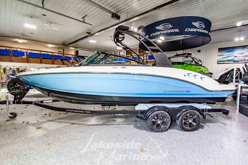Slide: The Image of 2026 Chaparral 23 SSi boat in showroom, blue and white design on trailer. - 6
