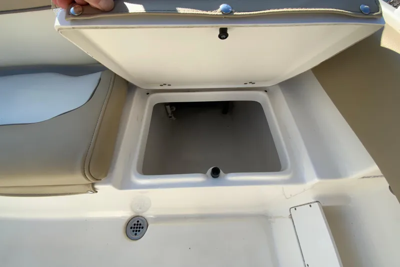 Slide: The Image of 2019 Key West 239 FS boat storage compartment with open lid and beige seating. - 18