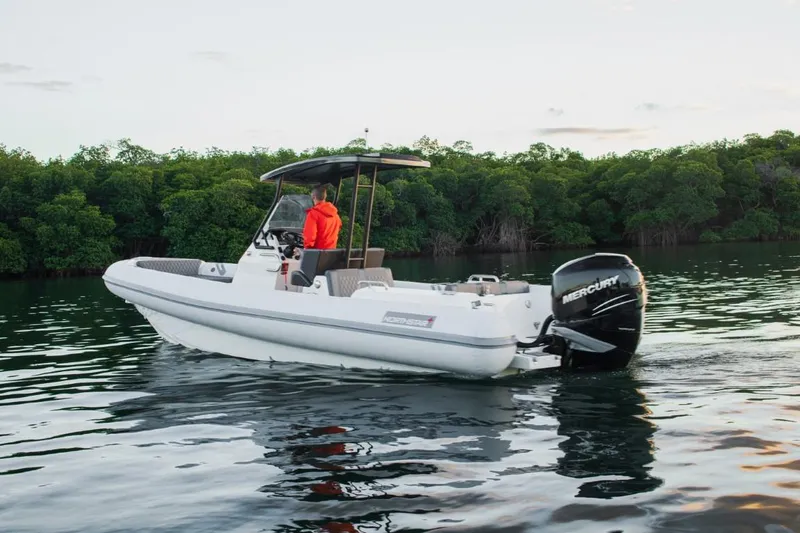 Slide: The Image of 2024 Northstar Orion 8 boat cruising on calm water near lush green trees. - 2