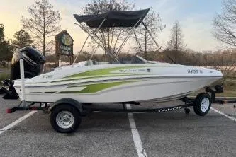 The Image of 2024 Tahoe T16 boat with green accents on a trailer in a parking lot. - 0