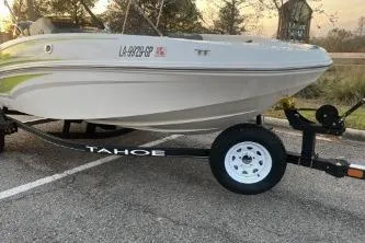 Slide: The Image of 2024 Tahoe T16 boat on trailer in parking lot at sunset. - 2