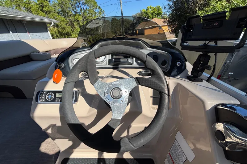 Slide: The Image of 2019 Sun Tracker Party Barge 20 DLX steering console with modern controls and seating. - 20
