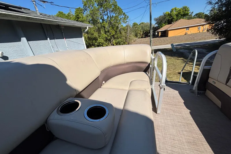 Slide: The Image of 2019 Sun Tracker Party Barge 20 DLX interior with beige seating and cup holders. - 30