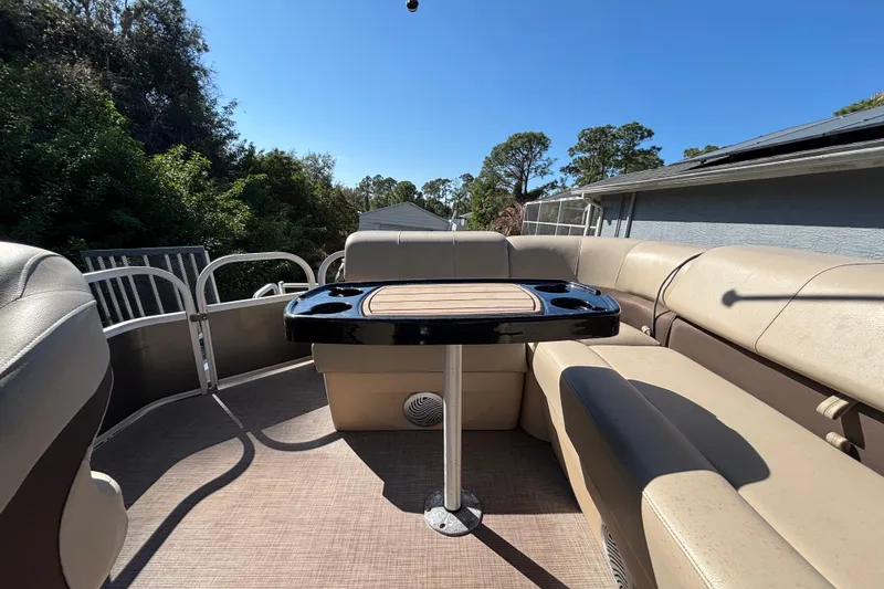 Slide: The Image of 2019 Sun Tracker Party Barge 20 DLX interior with table and seating under clear sky. - 65