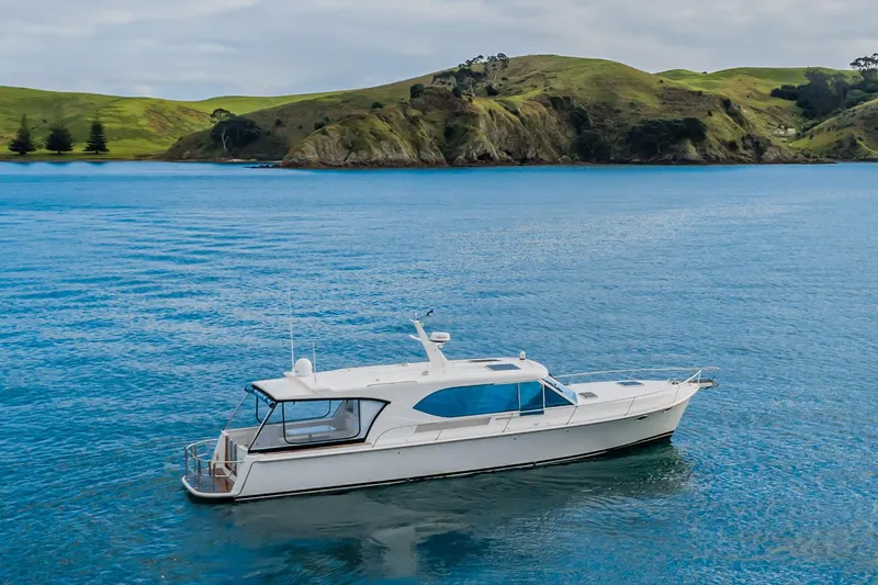 Slide: The Image of Manufacturer Provided Image: 2025 Hylas M49 yacht on serene blue water with scenic green hills in the background. - 9