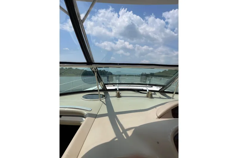 Slide: The Image of 2003 Sea Ray 550 Sundancer cockpit view with clear skies and scenic waterway. - 11
