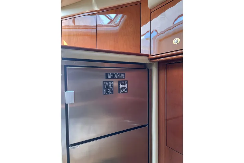Slide: The Image of 2003 Sea Ray 550 Sundancer yacht kitchen with stainless steel fridge and wooden cabinets. - 16