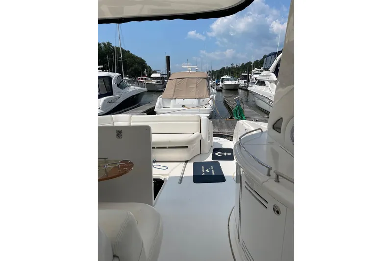 Slide: The Image of 2003 Sea Ray 550 Sundancer yacht interior at marina, featuring white seating and clear skies. - 5