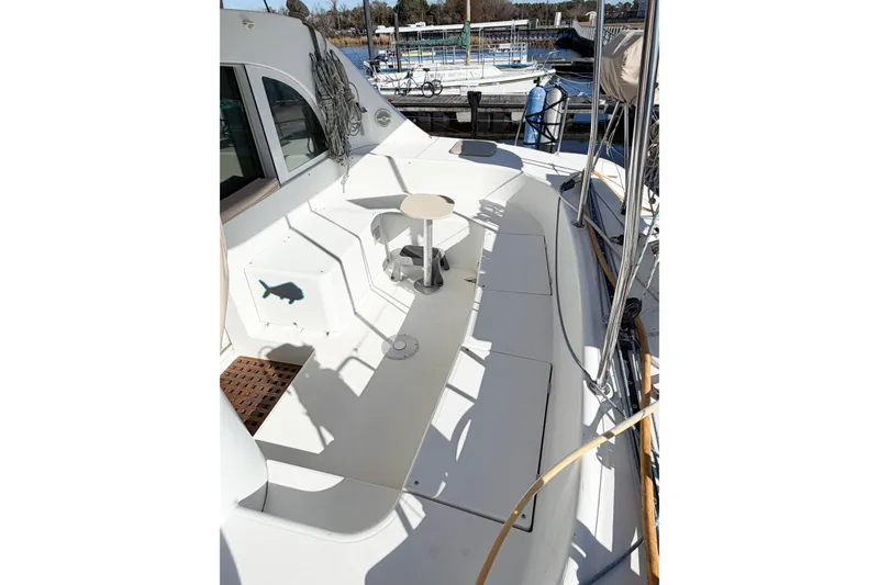 Slide: The Image of 2005 Lagoon 380 S2 yacht deck with seating and small table, docked at marina. - 10