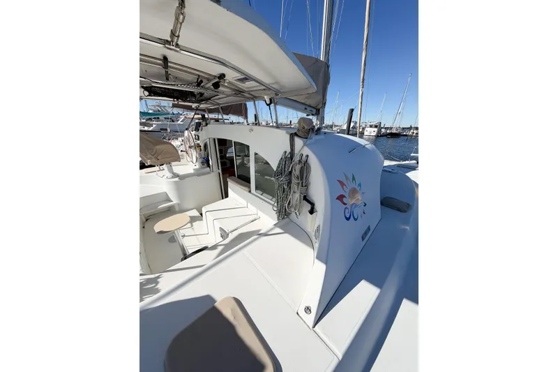 Slide: The Image of 2005 Lagoon 380 S2 catamaran docked at marina, featuring spacious deck and vibrant logo. - 12