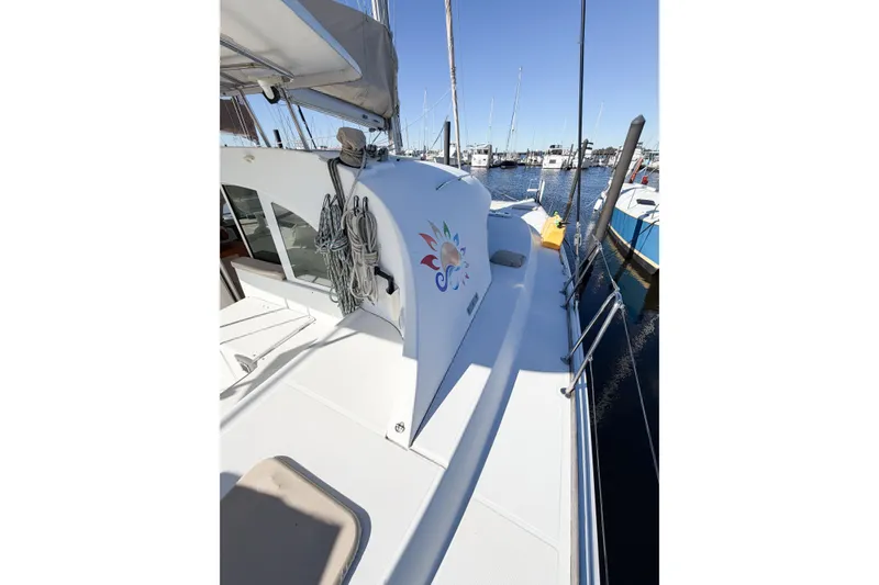 Slide: The Image of 2005 Lagoon 380 S2 catamaran docked at marina, featuring spacious deck and vibrant logo. - 13