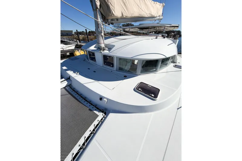 Slide: The Image of 2005 Lagoon 380 S2 catamaran with white deck and sails, docked in a marina. - 16