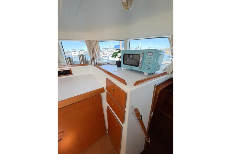 Slide: The Image of Interior of 2005 Lagoon 380 S2 yacht with microwave and wooden cabinetry. - 23