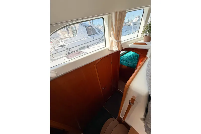 Slide: The Image of Interior view of 2005 Lagoon 380 S2 catamaran, featuring wooden cabinetry and a cozy cabin. - 28