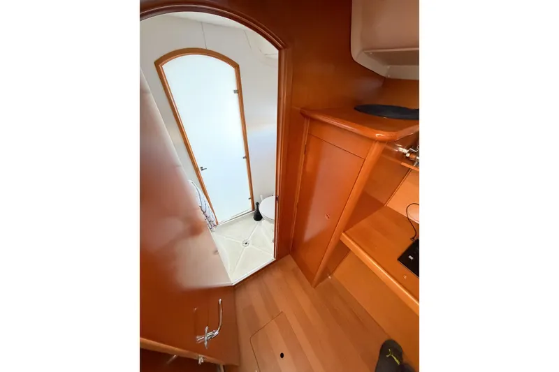 Slide: The Image of Interior view of 2005 Lagoon 380 S2 yacht, featuring wooden cabinetry and a compact bathroom. - 32