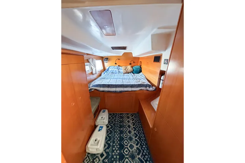 Slide: The Image of Cozy cabin interior of 2005 Lagoon 380 S2 catamaran with bed and wooden furnishings. - 34