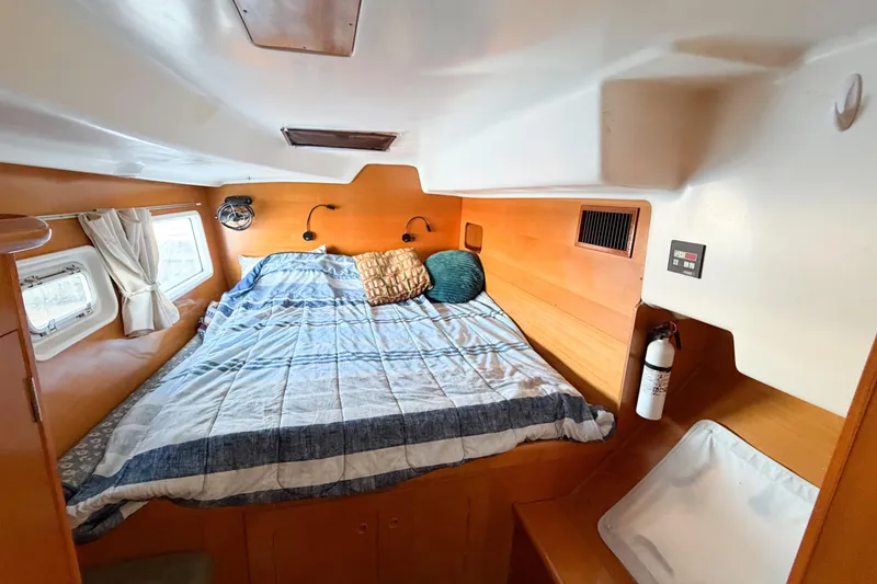 Slide: The Image of Cozy cabin interior of 2005 Lagoon 380 S2 catamaran with bed, porthole, and fire extinguisher. - 35