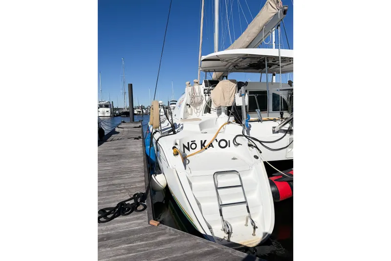 Slide: The Image of 2005 Lagoon 380 S2 catamaran docked at marina under clear blue sky. - 4