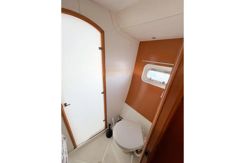 Slide: The Image of Bathroom interior of 2005 Lagoon 380 S2 catamaran with window and white door. - 43