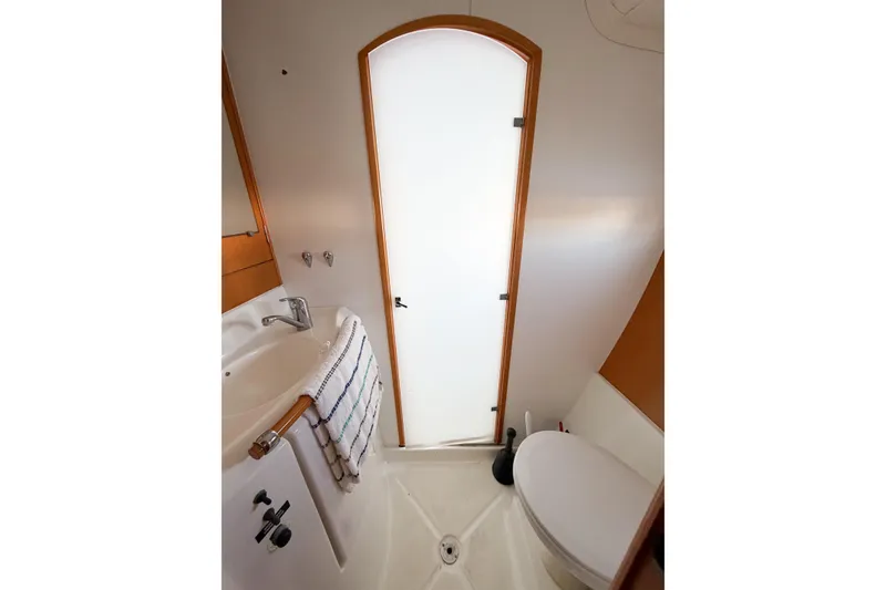 Slide: The Image of Compact bathroom in 2005 Lagoon 380 S2 yacht, featuring sink, toilet, and frosted door. - 44