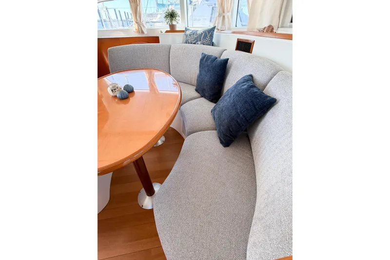 Slide: The Image of Interior of 2005 Lagoon 380 S2 yacht with curved seating and wooden table. - 53