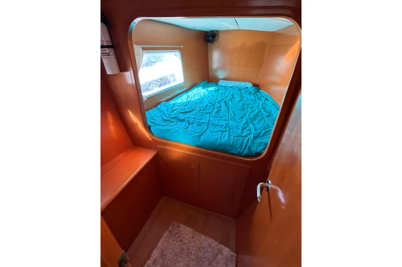 Slide: The Image of Cozy cabin interior of 2005 Lagoon 380 S2 catamaran with blue bedding and wooden finish. - 55