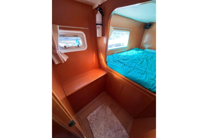 Slide: The Image of Interior cabin of 2005 Lagoon 380 S2 catamaran with bed and porthole windows. - 56
