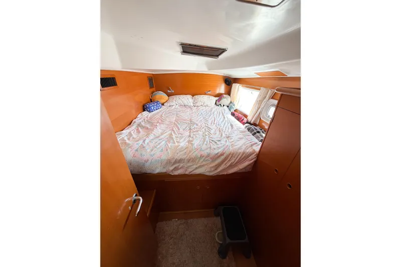 Slide: The Image of Cozy bedroom interior of 2005 Lagoon 380 S2 catamaran with wooden finish and porthole window. - 59