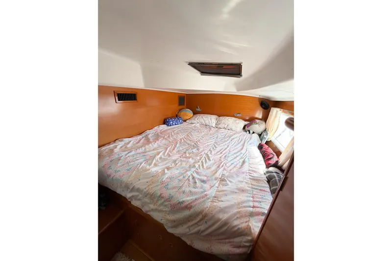 Slide: The Image of Cozy cabin bedroom in 2005 Lagoon 380 S2 catamaran with patterned bedding and natural light. - 61