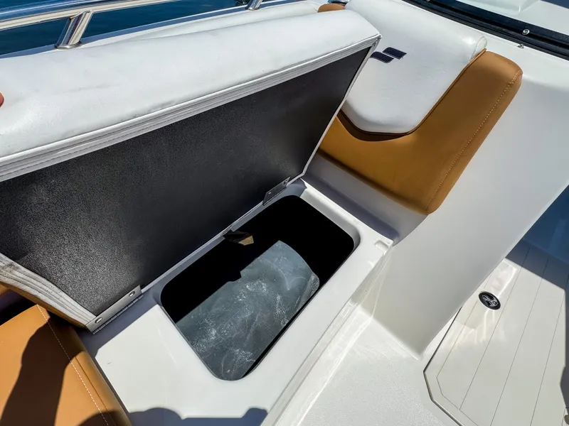 Slide: The Image of 2023 Starcraft SVX 190 OB boat storage compartment with open lid, featuring white and tan seating. - 16