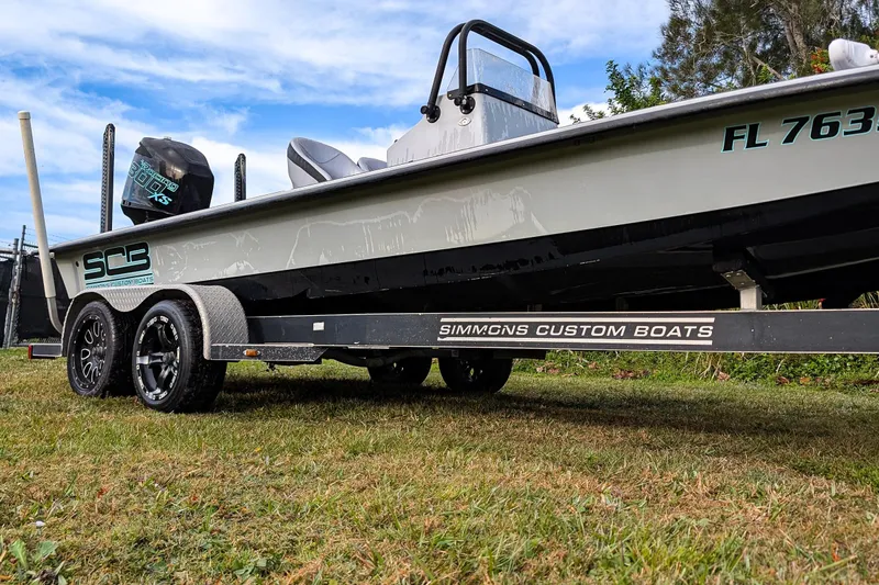 Slide: The Image of 2014 SCB Stingray Sport 25 boat on trailer, grassy area, clear sky background. - 17