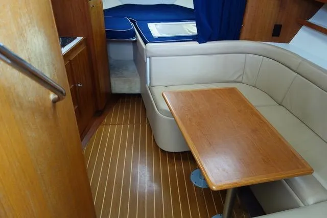 Slide: The Image of 2001 Tiara Yachts 3100 Open interior with wood table, beige seating, and blue bedding. - 12