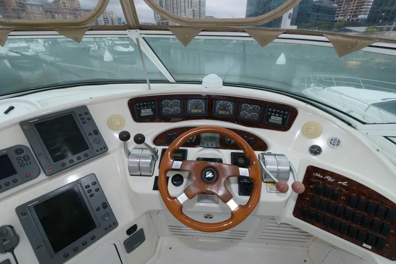 Slide: The Image of 2001 Sea Ray 540 Cockpit Motor Yacht helm with advanced navigation controls and wood-accented steering wheel. - 21
