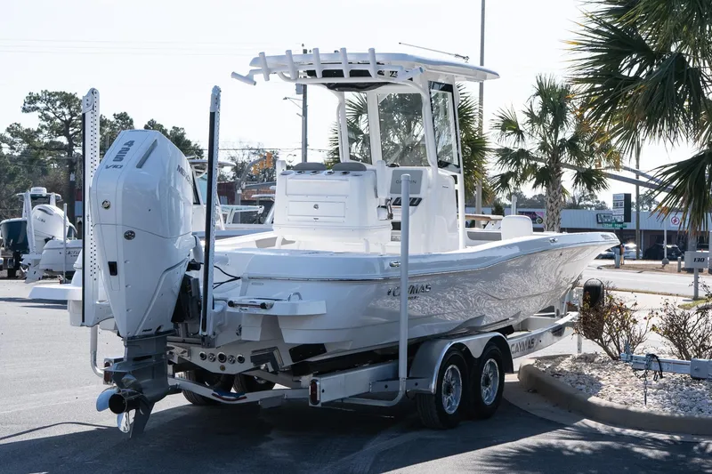 Slide: The Image of 2026 Caymas 28 HB boat on trailer, parked outdoors near palm trees. - 6