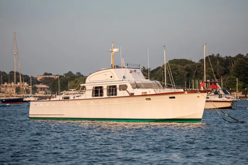 The Image of 1964 Huckins Out Islander 56 yacht anchored in a scenic harbor. - 0