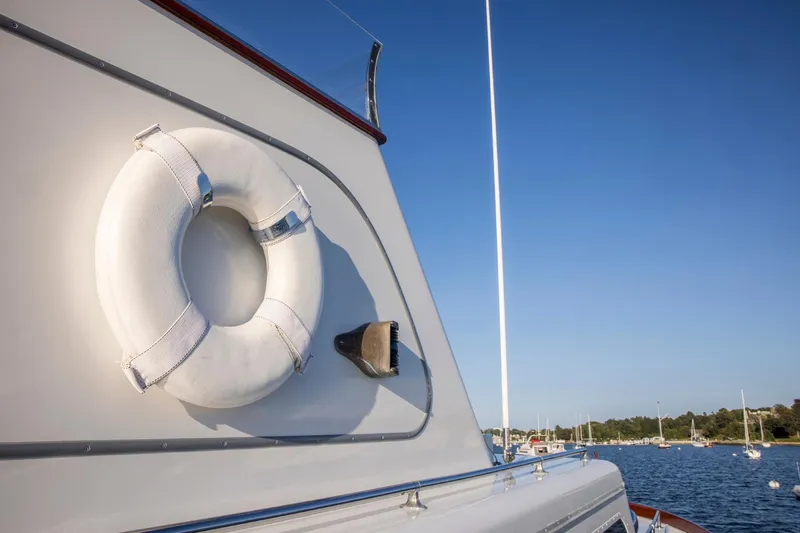 Slide: The Image of 1964 Huckins Out Islander 56 yacht with lifebuoy, docked in a serene harbor. - 10