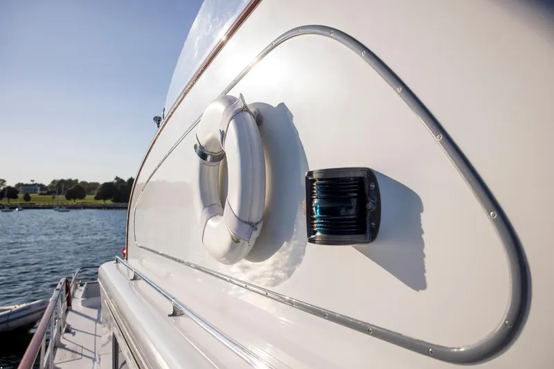 Slide: The Image of 1964 Huckins Out Islander 56 yacht with lifebuoy, docked by the water. - 11