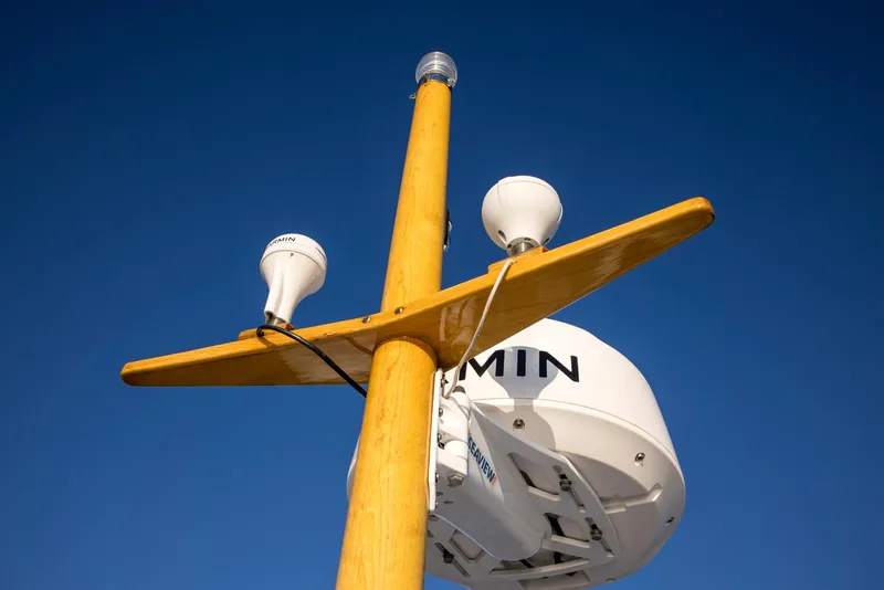 Slide: The Image of Wooden mast with radar and antennas on 1964 Huckins Out Islander 56 against clear blue sky. - 19