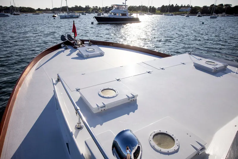 Slide: The Image of 1964 Huckins Out Islander 56 yacht on calm water, with scenic harbor view. - 2
