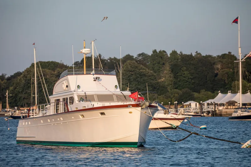 Slide: The Image of 1964 Huckins Out Islander 56 yacht anchored in a serene harbor setting. - 20